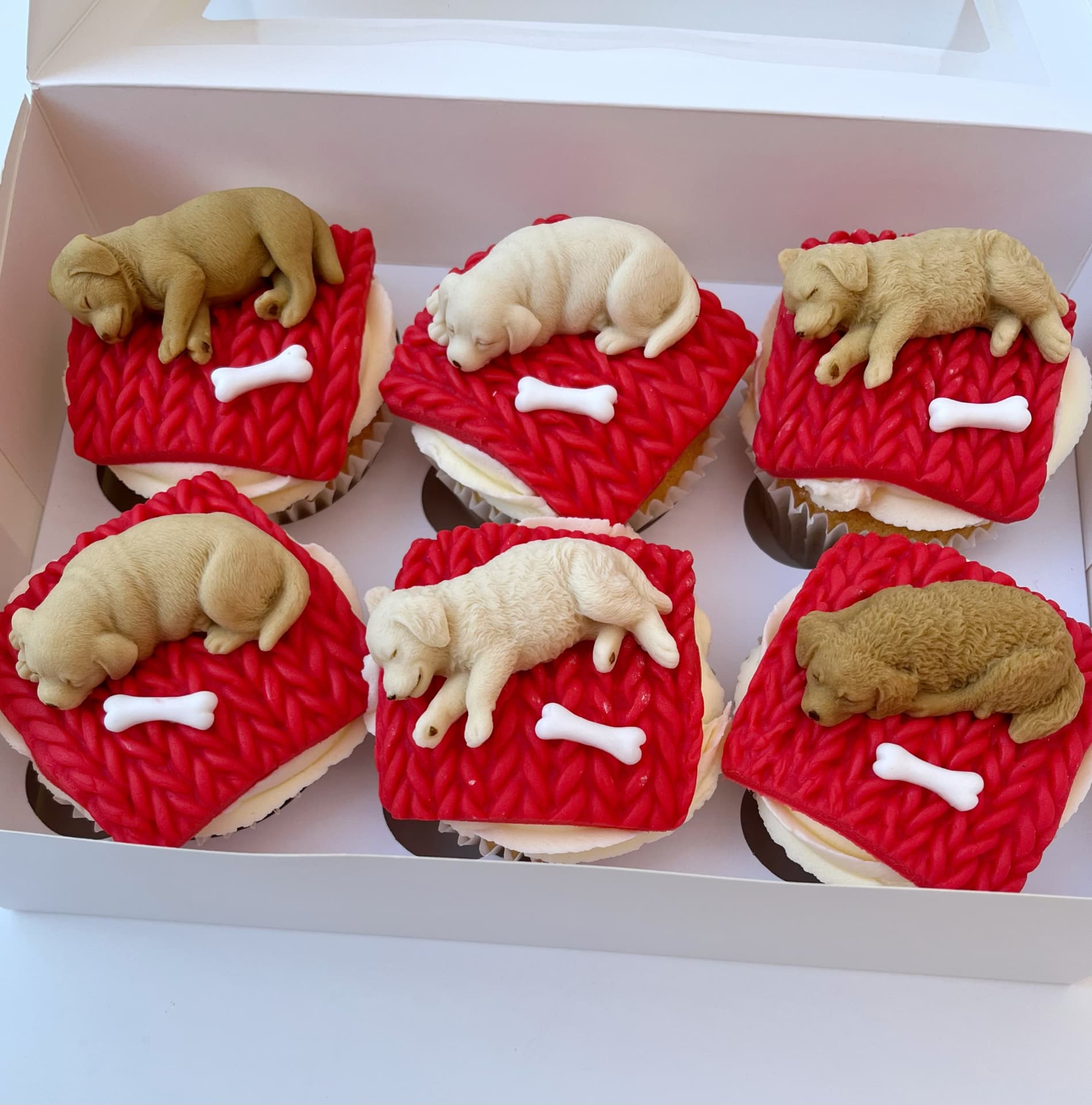 Cupcakes topped with handmade sleeping puppy toppers on knitted blankets