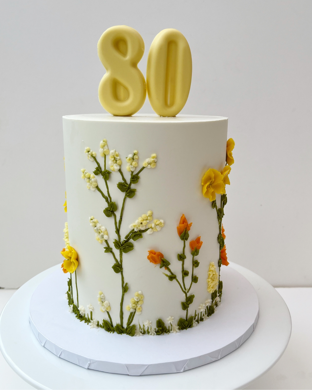 80th birthday cake with piped buttercream wildflowers and chocolate numbers