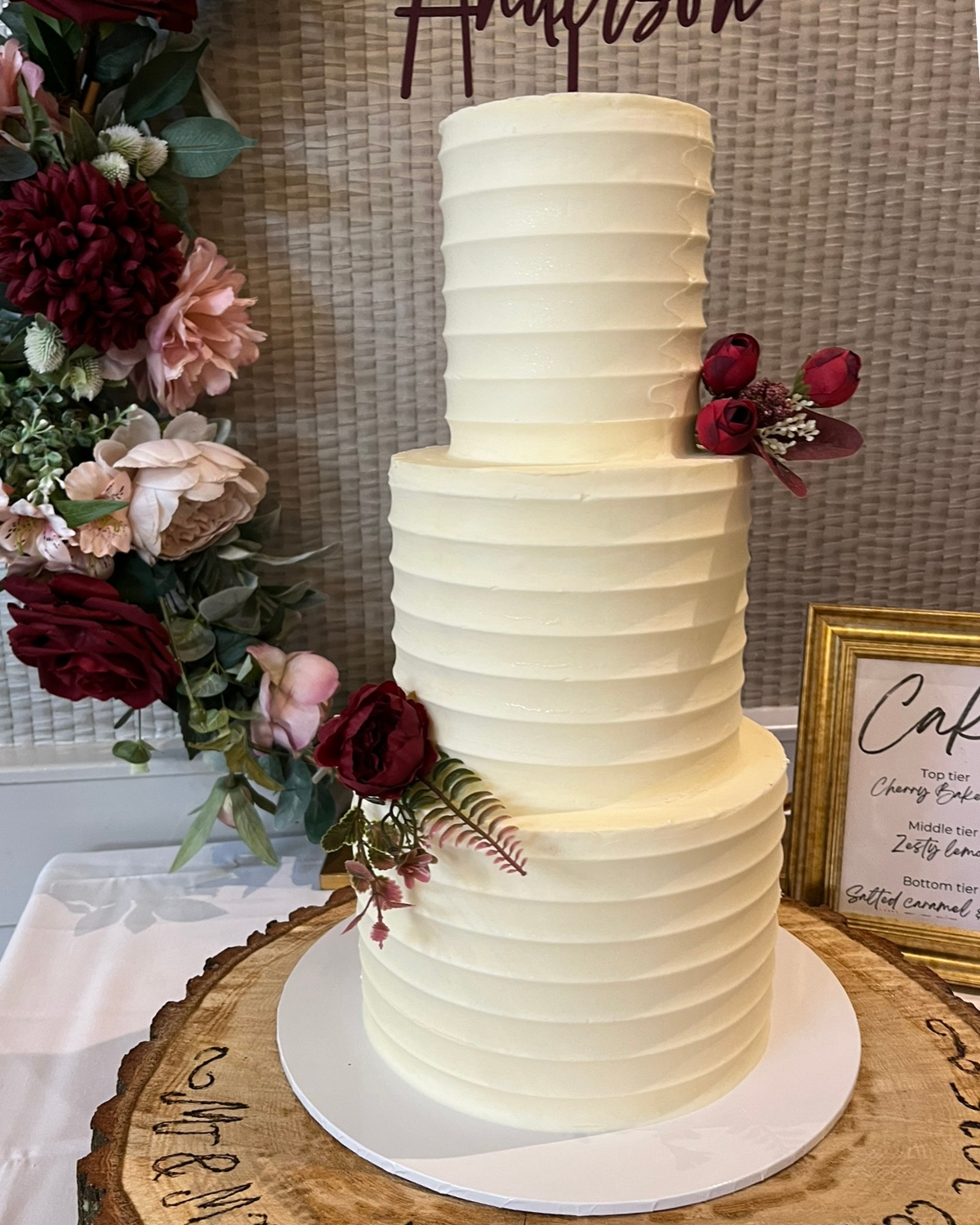 Three tier ivory wedding cake with burgundy and blush flowers
