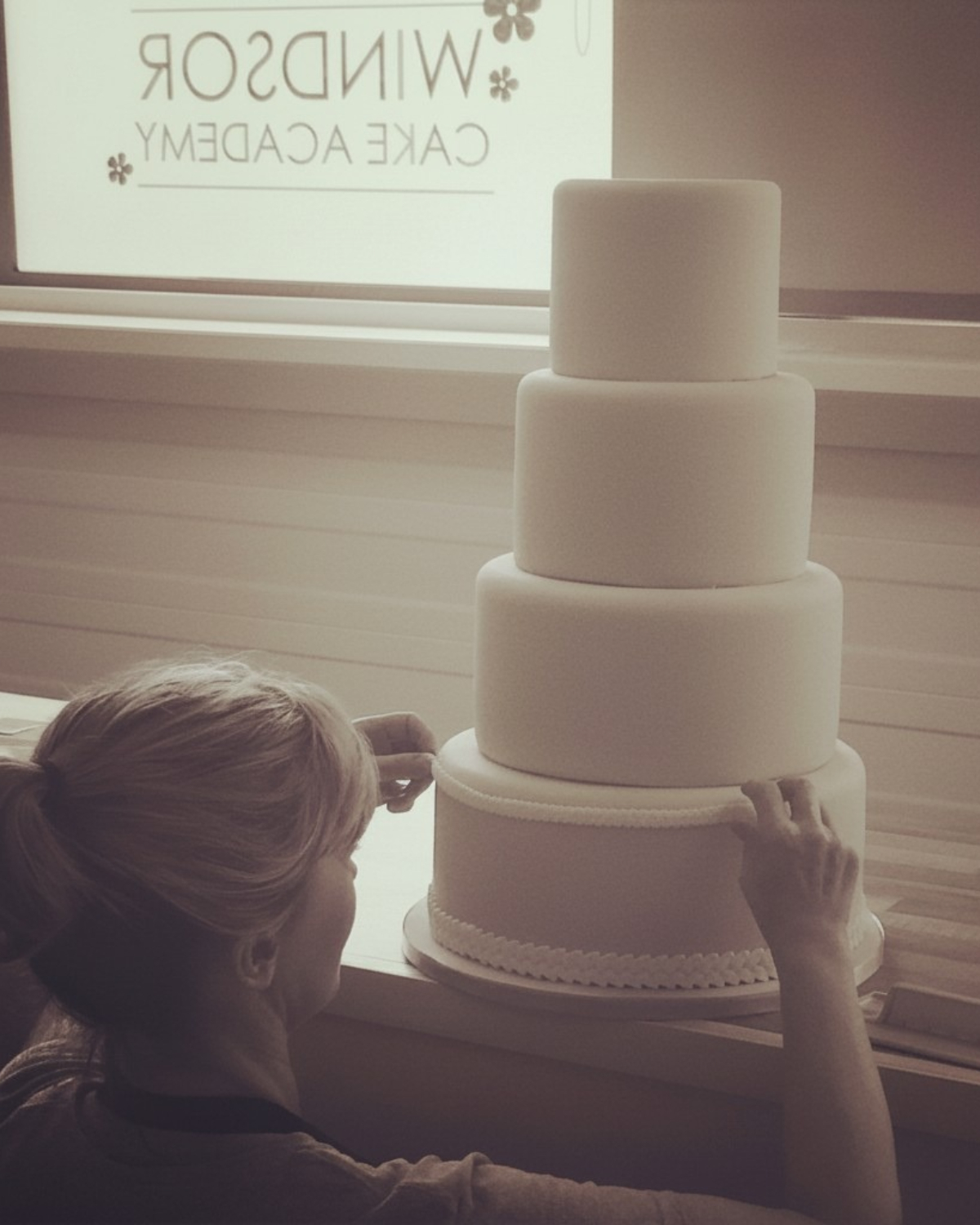 Sharon Burchall decorating a four-tier wedding cake at Windsor Cake Craft